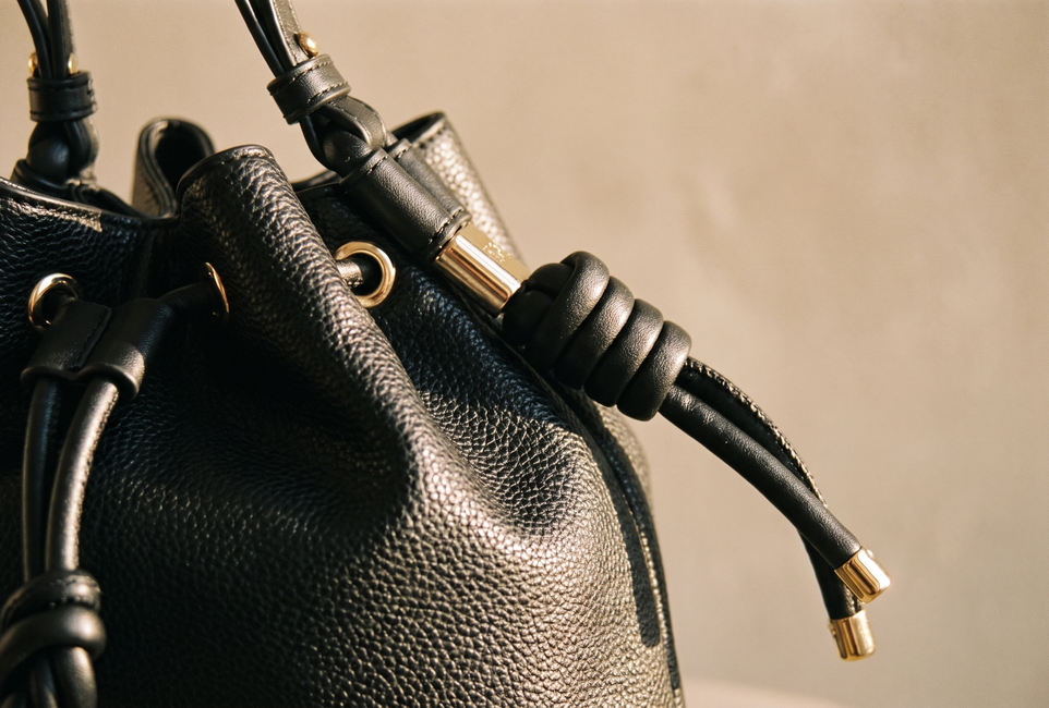 Close view of a black bag's knotted handle and hardware