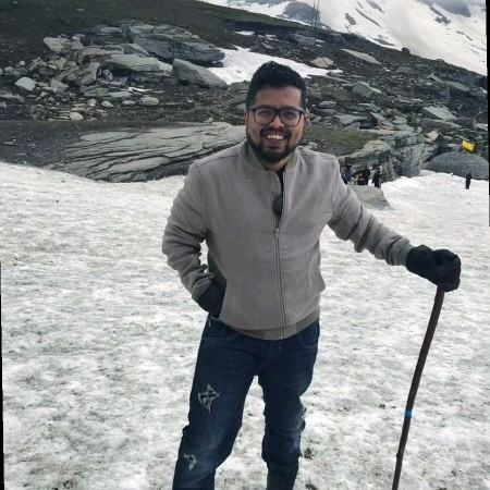 Sanjeev smiling outdoors in a snowy mountain landscape